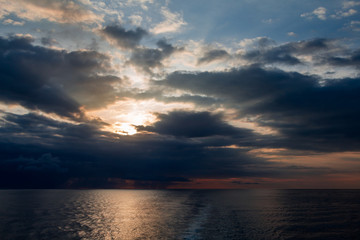 Naklejka na ściany i meble Sunrise breaking through the clouds over the ocean 