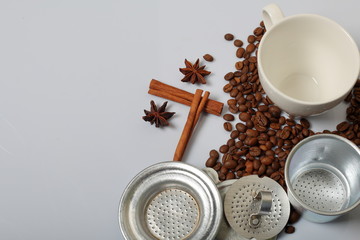 Coffee beans, cinnamon sticks, allspice and anise. Near a white cup. On white background. World Coffee Day.