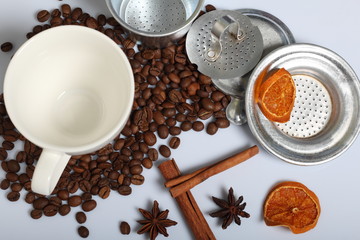Coffee beans, cinnamon sticks, allspice and anise. Nearby is a white cup and slices of dried oranges. On white background. World Coffee Day.