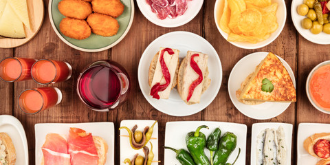A panorama of Spanish tapas. Wine, jamon, gazpacho, tortilla and other snacks, shot from the top on a dark rustic wooden background