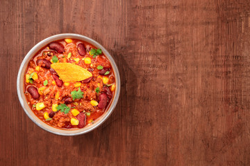 Chili con carne, shot from above on a dark rustic wooden background with a place for text