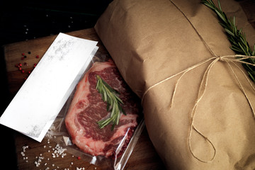 Raw beef steak vacuum Packed on wooden table, mockup for butcher shop or logo