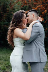 Fototapeta premium Young couple in love outdoor. Young couple in celebrate outfits among the branches of sea buckthorn. A loving couple, a guy and a girl kiss and hug. Happy lovers and family. Love story. 