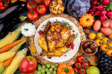 Baked chicken for Thanksgiving Day. Roasted whole chicken or turkey with autumn vegetables and fruits for thanksgiving dinner on wooden table. Healthy food for Thanksgiving Day