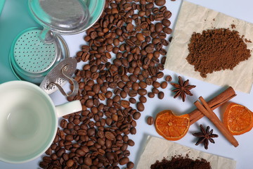 Coffee beans, cinnamon sticks, allspice and anise. Nearby is a white cup and slices of dried oranges. On white background. World Coffee Day.