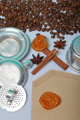 Coffee beans, cinnamon sticks, allspice and anise. Nearby are slices of dried oranges. Paper filter for coffee. On white background. World Coffee Day.