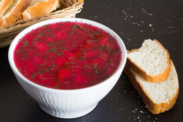 Close up beetroot soup in white bowl on black background