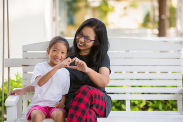 Kindness mom happy playing with daughter on swing chair