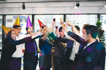 Group of office workers celebrating winter holidays together at work. Businessman drinking champagne at office. Merry Christmas and Happy New Year.