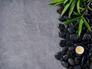 Fototapeta premium Scented candles and bamboo leaves on pebbles.