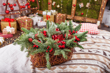 Christmas decor. Holiday basket with fir tree  branches and red balls on background og Christmas light. Winter holidays.