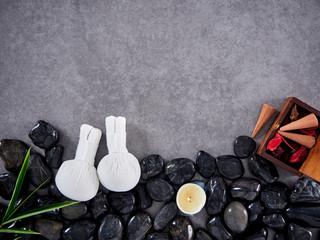 Herbal compress ball place on black pebbles.
