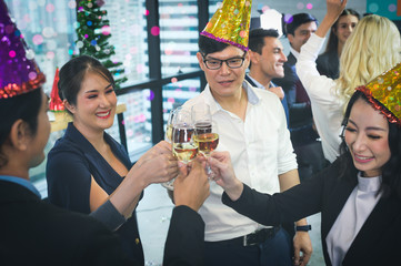 Group of office workers celebrating winter holidays together at work. Businessman drinking champagne at office. Merry Christmas and Happy New Year.