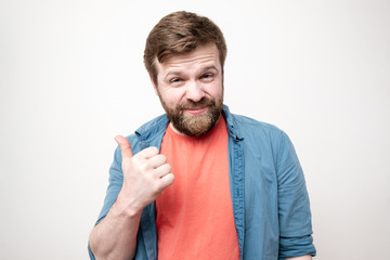 Portrait of a sarcastic, cunning bearded man showing thumb up gesture, on a white background.