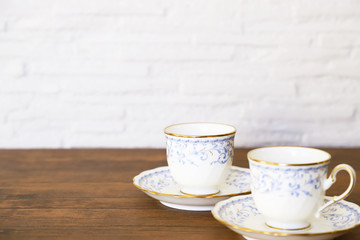 白い壁の背景に木製テーブル。その上に置かれたコーヒーカップ