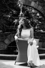 Black and white portrait of young woman in dress standing outdoor, smiling. Long beautiful hair waving, natural makeup. Pretty face. Attractive young sexy woman enjoying her time.