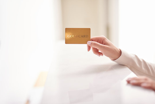 Young woman holding gold card on white blurred background
