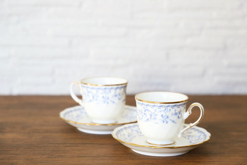 白い壁の背景に木製テーブル。その上に置かれたコーヒーカップ