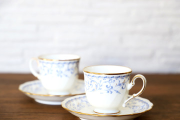 白い壁の背景に木製テーブル。その上に置かれたコーヒーカップ