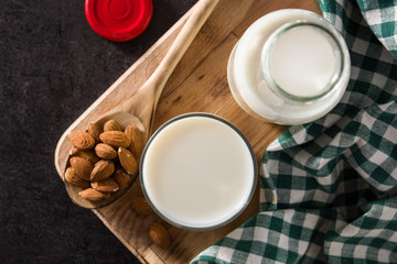 Organic almond milk in glass and bottle on black background.Top view