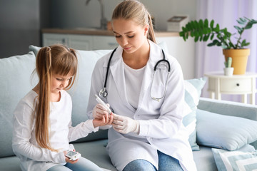 Doctor taking blood sample of diabetic girl at home