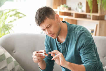 Diabetic man checking blood sugar level at home © Pixel-Shot