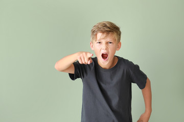 Portrait of angry little boy on color background