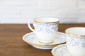 白い壁の背景に木製テーブル。その上に置かれたコーヒーカップ