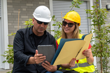 Male and female civil engineers sitting outdoors analyzing projects