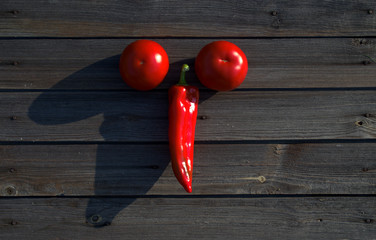 Hot red pepper with two tomatoes on a dark wooden background