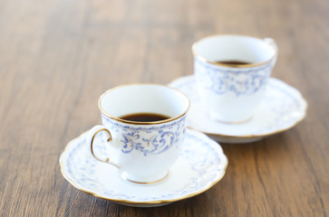 白い壁の背景に木製テーブル。その上に置かれたコーヒーカップ