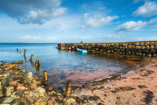 A small boat moored at an old stone jetty at Sannox
