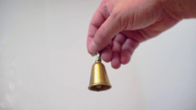 hand shakes a small yellow metal bell.close-up.shallow depth of field.