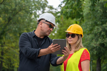 Architect and builder or surveyors discussing about the building location for an ecological forest...