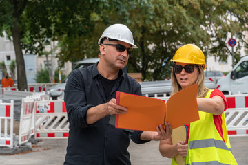 Obraz premium Male and female civil engineers checking plans and projects on construction site