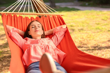 Fototapeta na wymiar Beautiful young woman resting in hammock outdoors