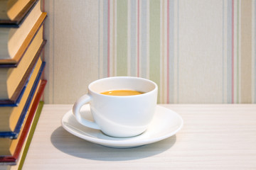 A stack of books and a Cup of espresso on a white table