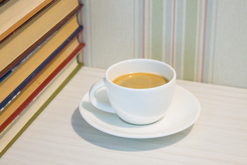 A stack of books and a Cup of espresso on a white table