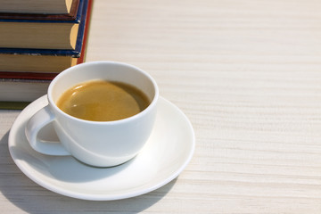 A stack of books and a Cup of espresso on a white table