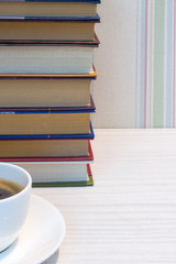 A stack of books and a Cup of espresso on a white table