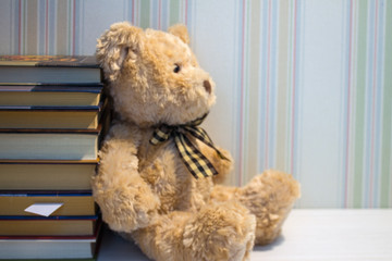 A stack of books and a plush bear on a white table