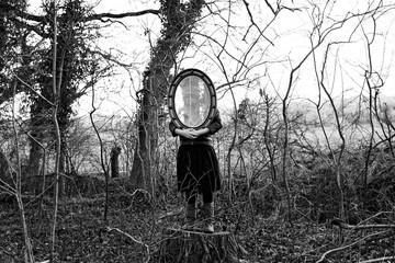 Girl holding a mirror in the woods