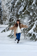 Fototapeta na wymiar Girl runs through the snow in the woods.Caucasian girl