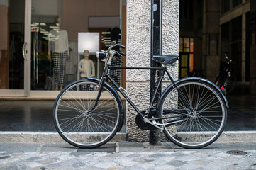 Black bike in front of fashion shop on italian street.
