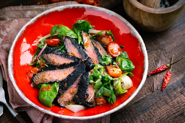 Fillet of beef smoked brisket with green salad on wooden table. Roasted Beef cooking idea