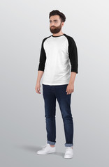 Bearded male model wearing white and grey 3/4 sleeve raglan shirt in dark blue denim jeans pant. isolated background