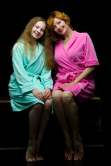 Daughter and mother in bathrobes posing in the studio. The conce