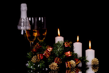 Two glasses with champagne, bottle, candle and Christmas ornaments