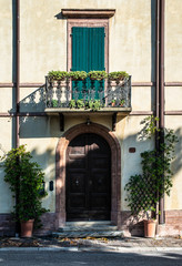 Italian style house facade. Door and terrace with flowers.