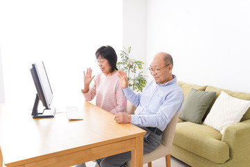 パソコンでテレビ電話をする高齢の夫婦